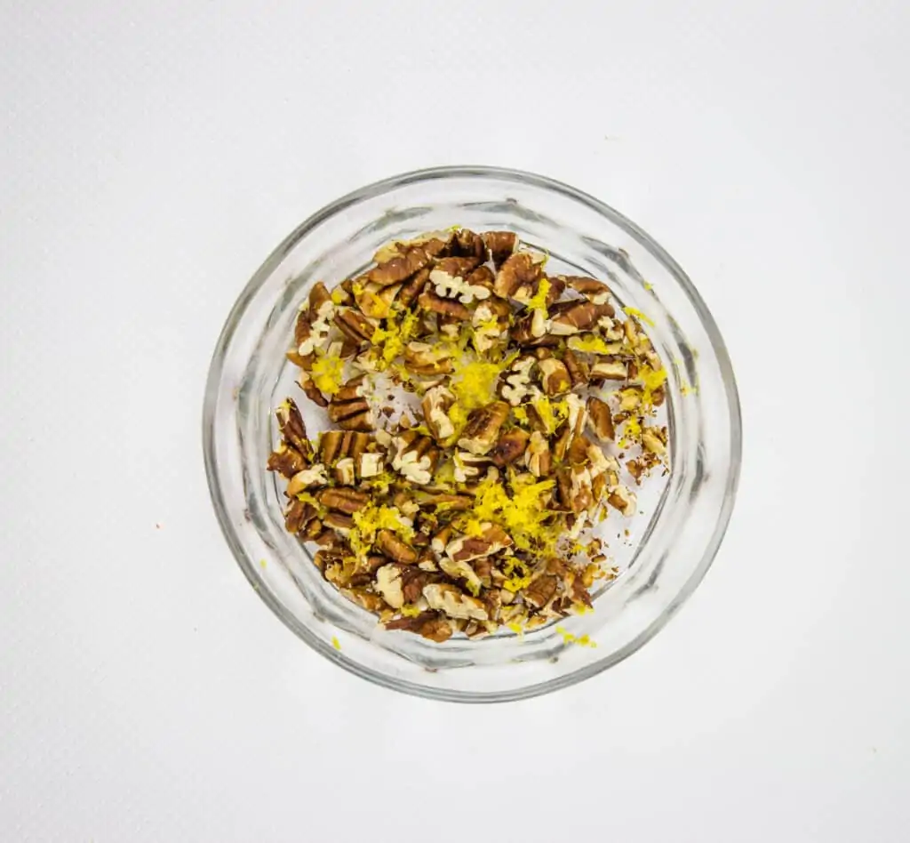 A small bowl with mixed toasted pecans and lemon zest.