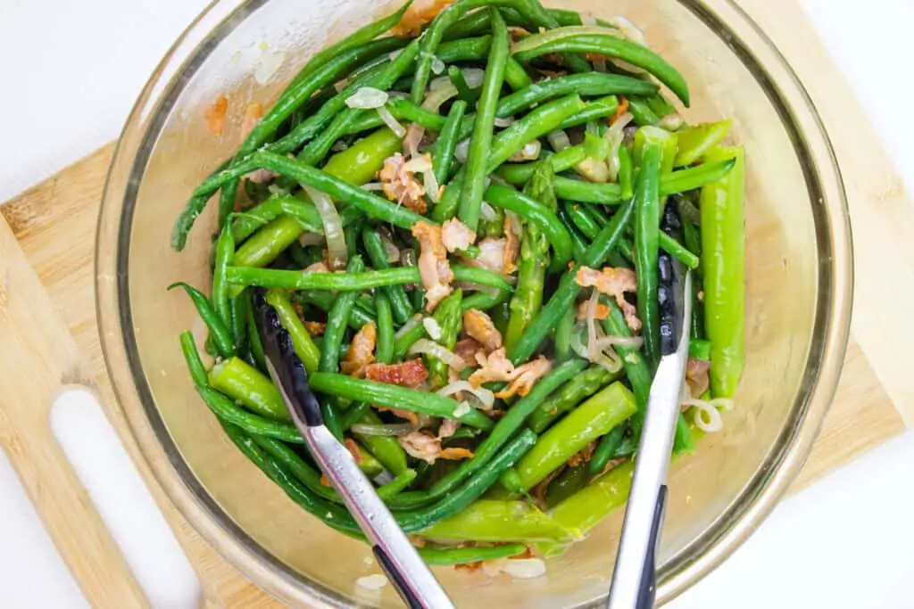 Beans, asparagus and bacon shallot mixture tossed in a bowl.