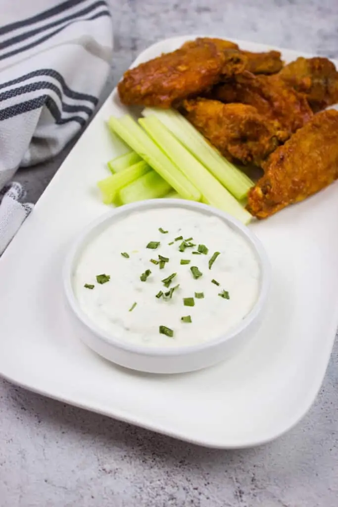 keto blue cheese dip in a bowl with celery sticks and buffalo wings