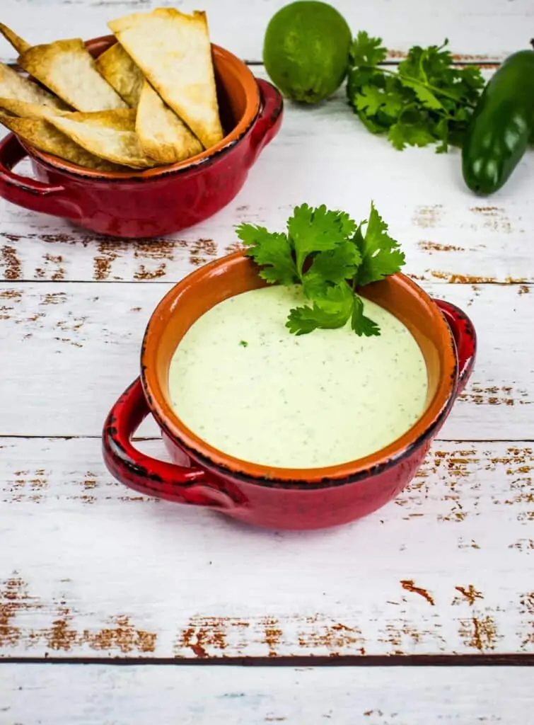 keto creamy jalapeno dip in a rustic bowl with tortilla chips in the background