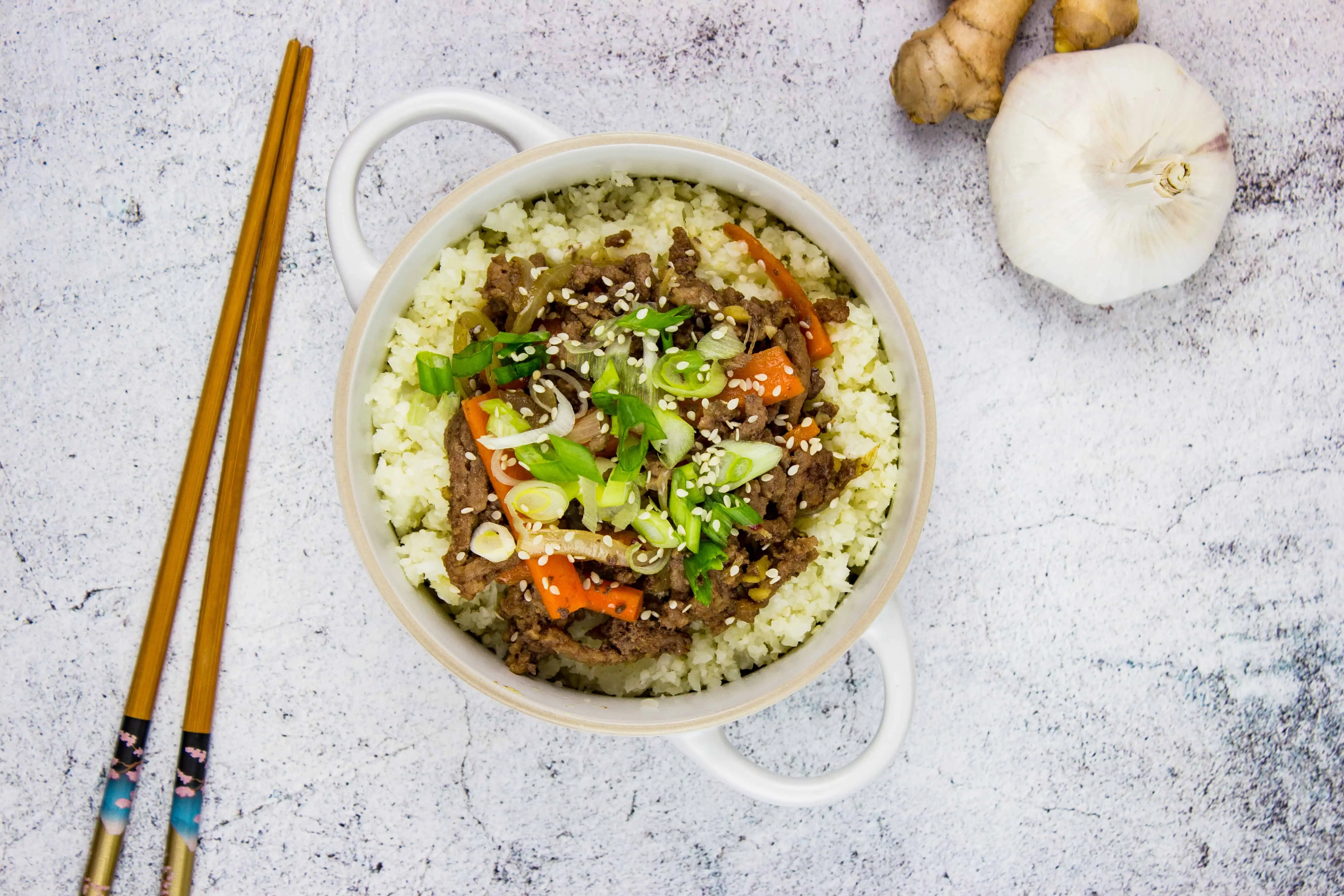 korean beef bowl with garlic and ginger in the background