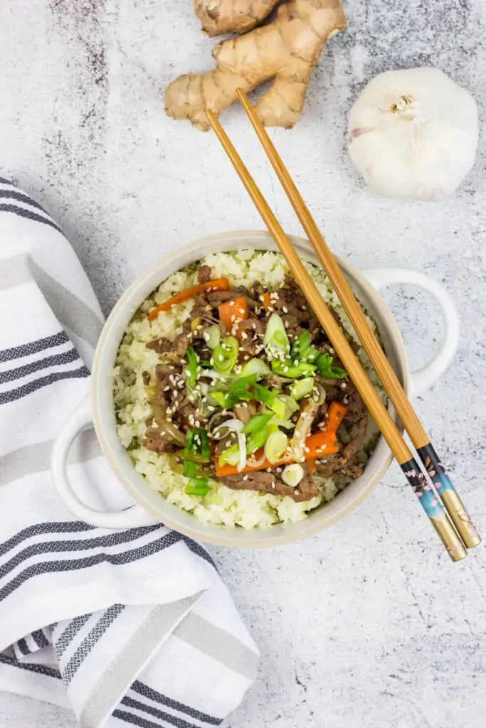 korean beef bowl with garlic and ginger in the background