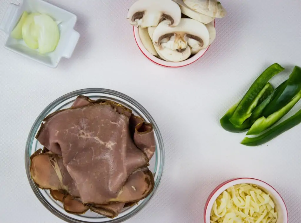 ingredients to make keto philly cheesesteak stacks - beef, mushrooms, onion, peppers, cheese