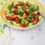 cucumber, tomato, avocado salad in a yellow serving dish