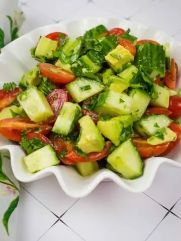 cucumber, tomato, avocado salad in a scalloped serving bowl