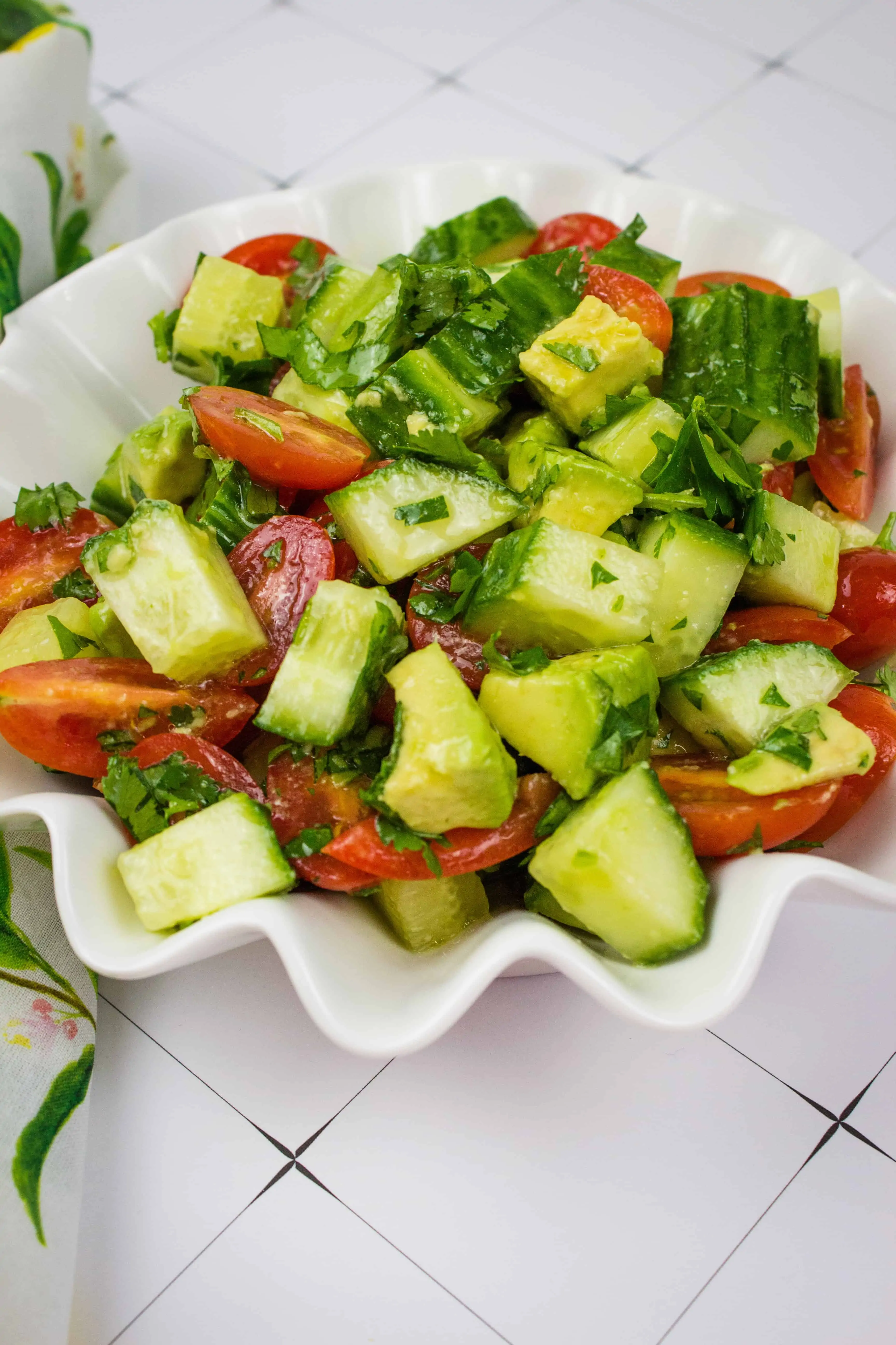 cucumber, tomato, avocado salad in a scalloped serving bowl