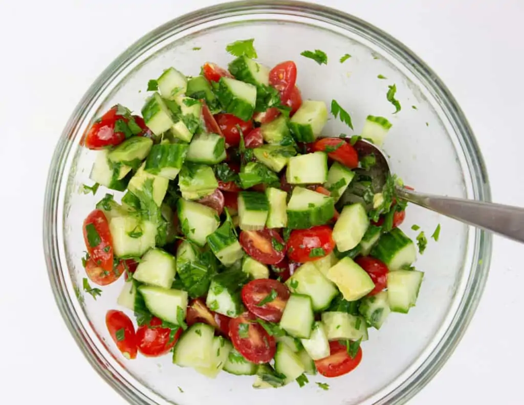 chopped veggies to make cucumber, tomato, avocado salad topped with teh dressing