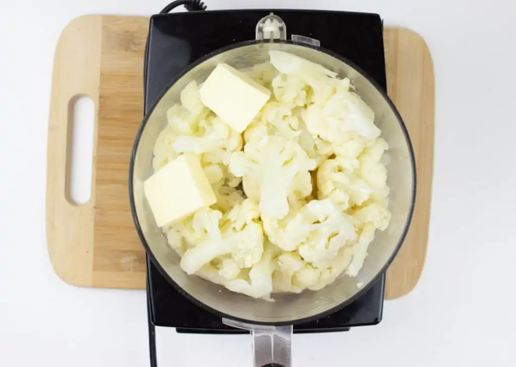 Butter, cheese, cauliflower, and cream in a food processor to make cheesy mashed cauliflower.