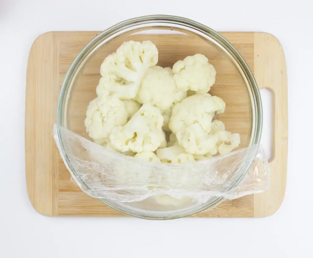 A touch of water added to a bowl with the cauliflower which is ready for steaming.