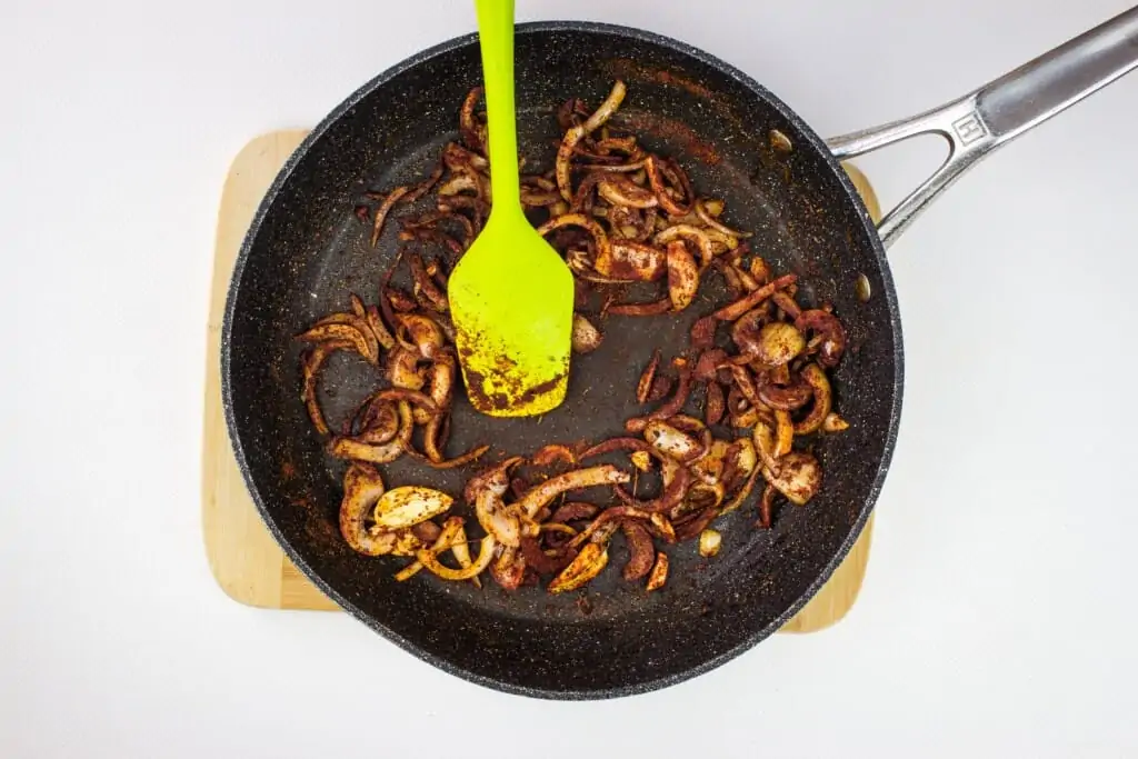 adding the spices to the onions in a skillet