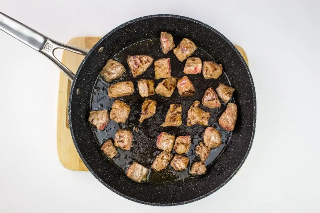 browning the beef in the oil in a black skillet