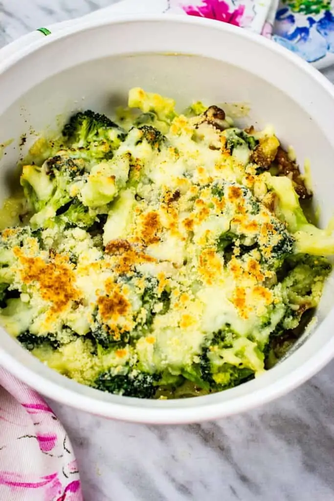 keto broccoli casserole with parmesan and bacon in a white round casserole dish