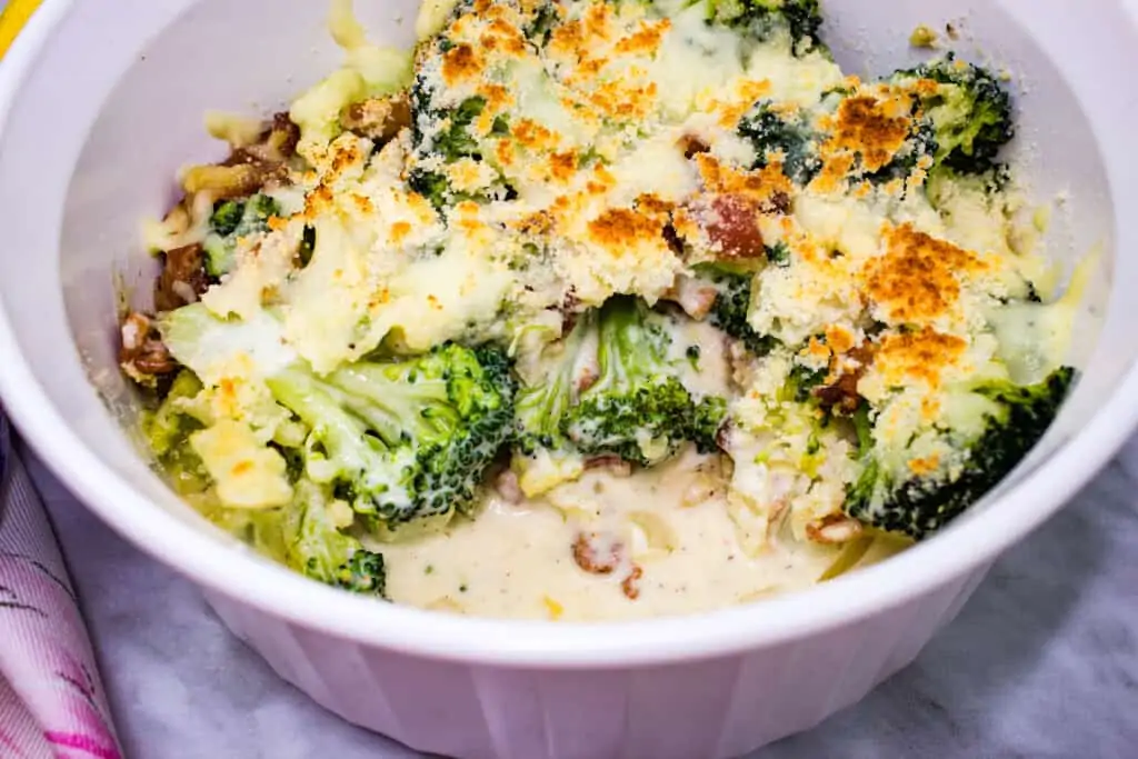 keto broccoli casserole with parmesan and bacon with a scoop missing from it