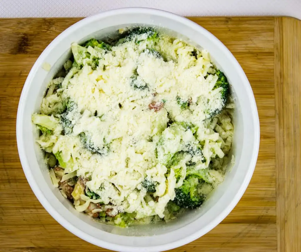 keto broccoli casserole with parmesan and bacon in a white casserole dish ready for the oven