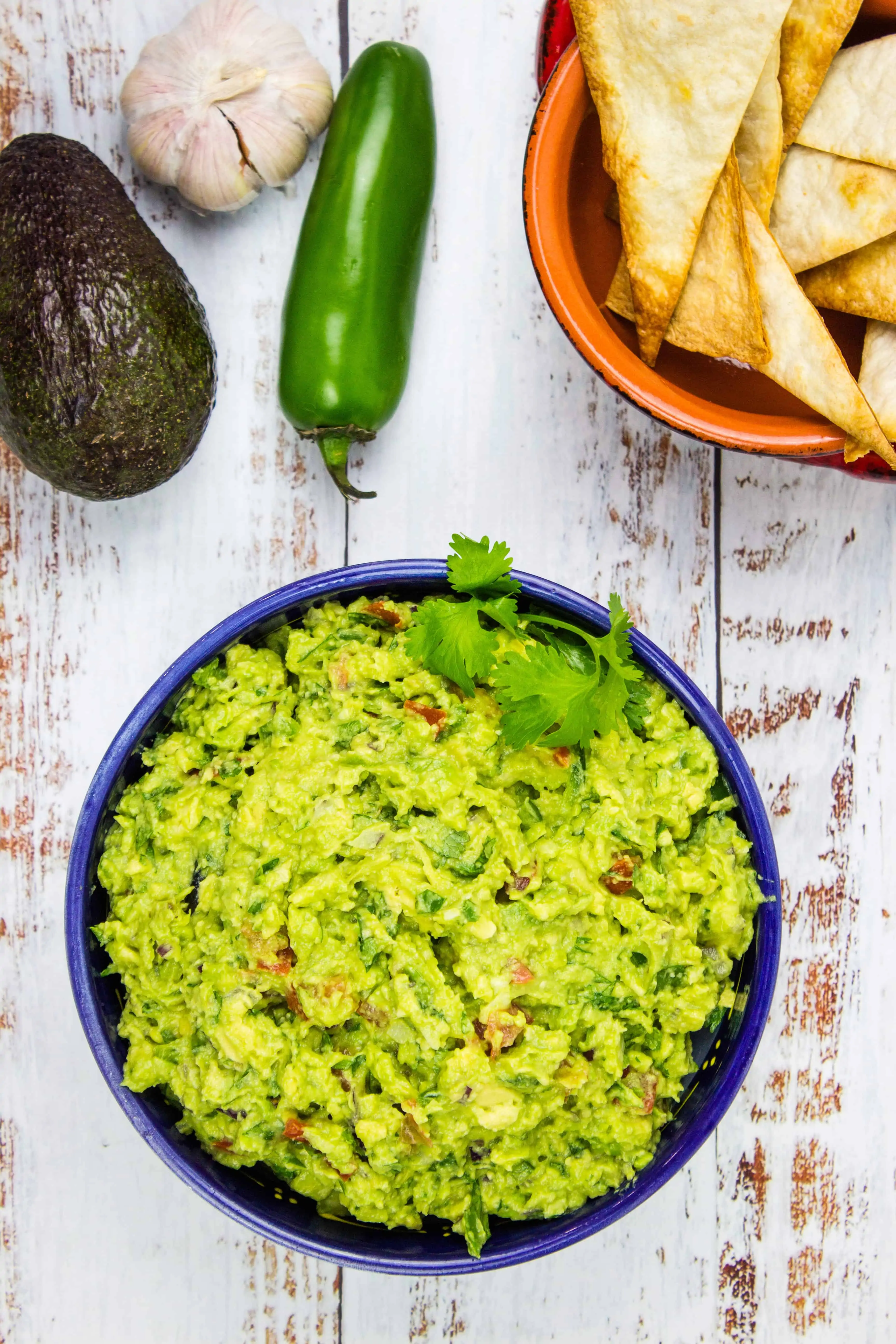 easy keto guacamole on a table with chips and veggies in the background.