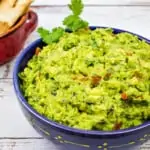 Easy keto guacamole in a bowl with low carb tortilla chips in the background
