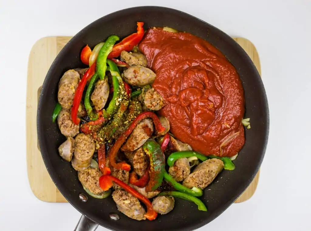 adding tomato sauce and spices to the skillet and heating it through