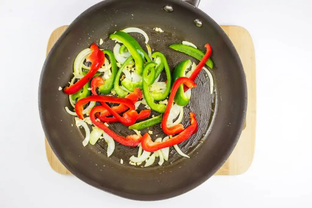 red and green peppers added to the skillet with cooked onions to make keto sausage stew