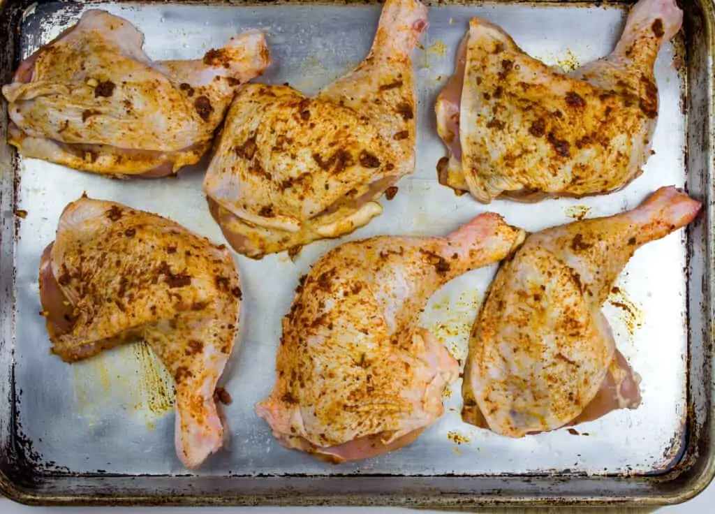 Peruvian chicken rubbed with the spice mixture and lying flat on a sheet pan.
