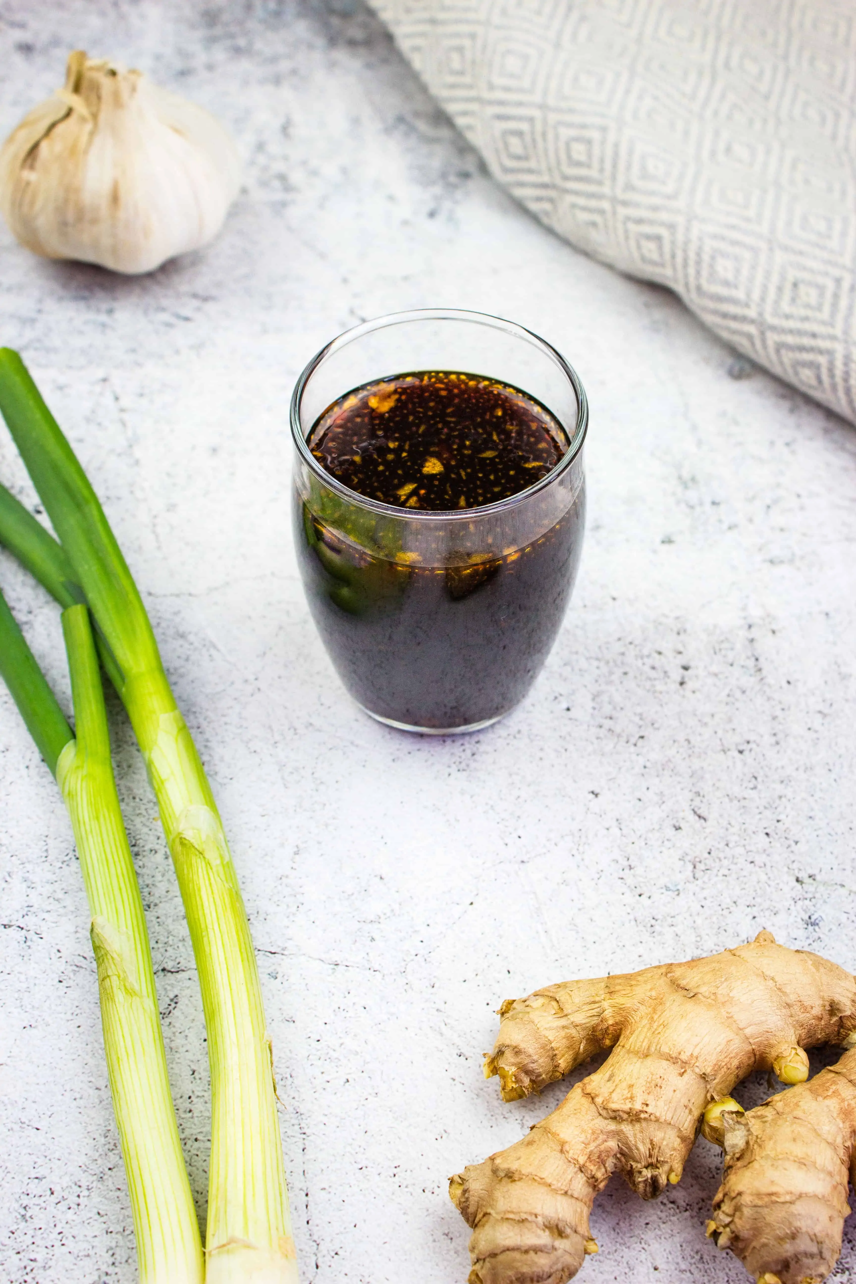 keto teriyaki sauce in a glass jar with scallions, ginger and garlic nearby