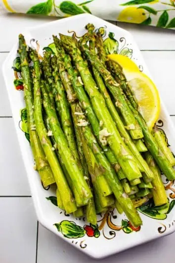 air fryer asparagus on a platter with a lemon wedge