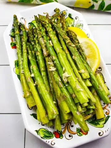 air fryer asparagus on a platter with a lemon wedge