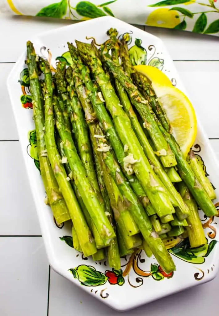 air fryer asparagus on a platter with a lemon wedge