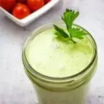 keto green goddess dressing in a jar with tomatoes in the background