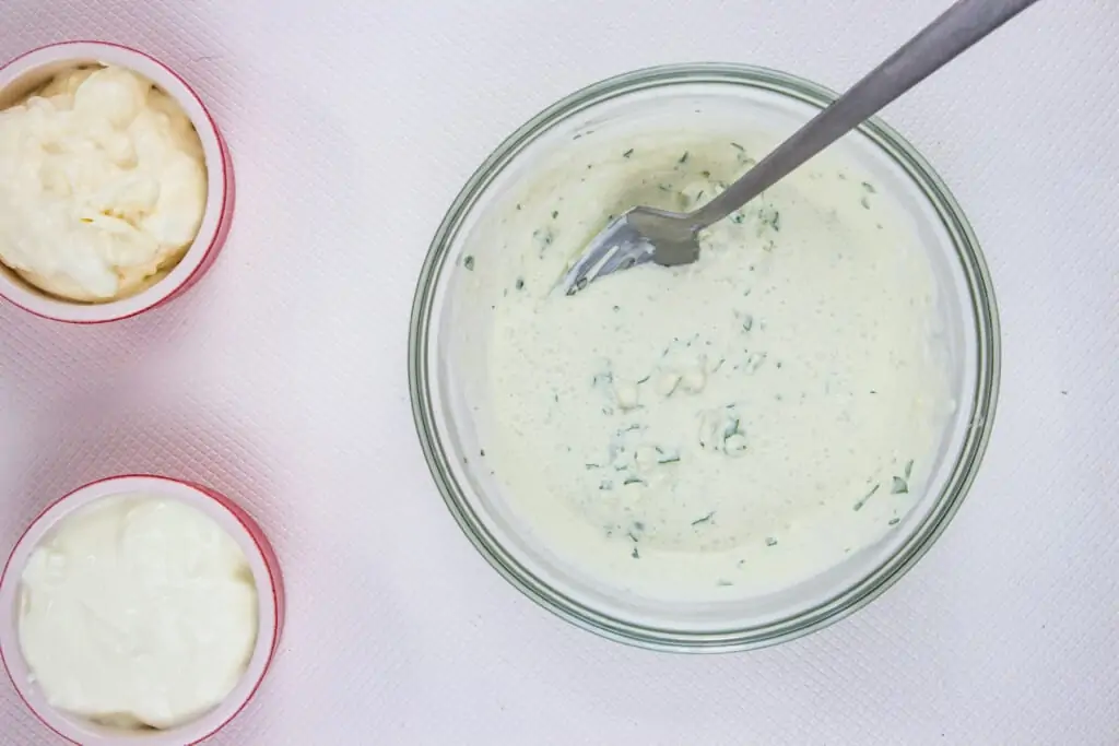 A bowl with keto blue cheese dressing and blue cheese on the side.