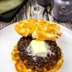 a keto butter burger on a plate with pickle and lettuce in the background