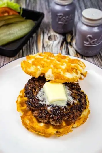 a keto butter burger on a plate with pickle and lettuce in the background