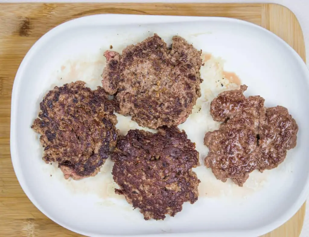 four portions of seared keto butter burgers ready for chaffle buns