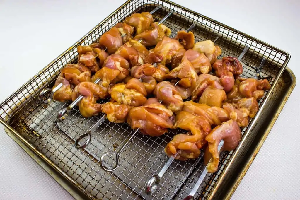 teriyaki chicken skewered and on an air fryer sheet