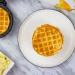cirspy keto chaffles on a plate with another in the chaffle maker in the background