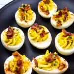 keto deviled eggs with bacon on a black platter
