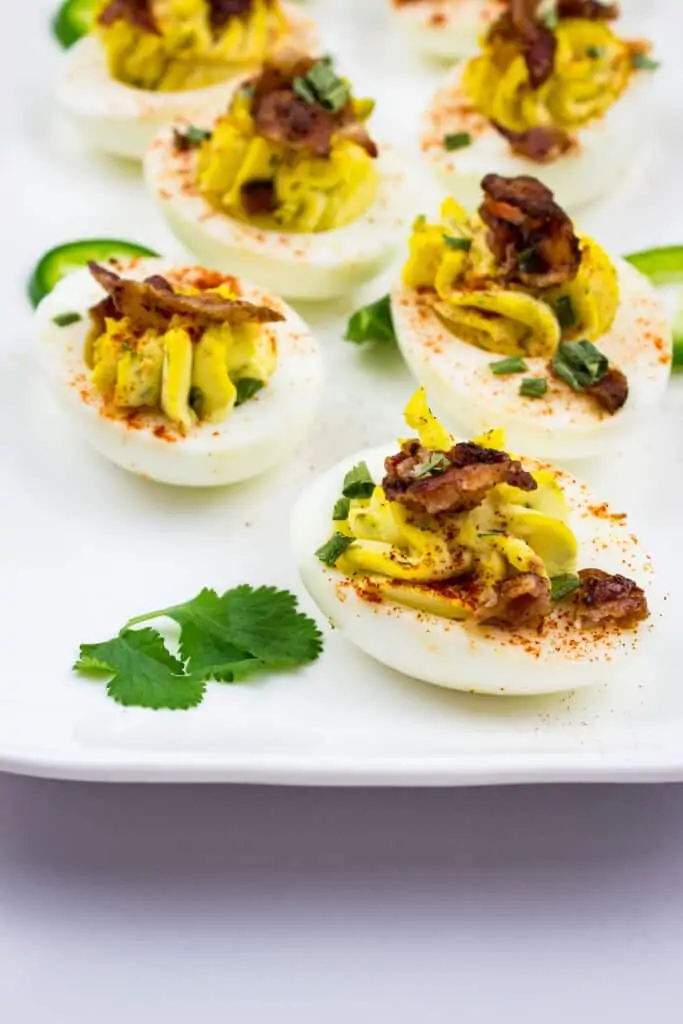 keto deviled eggs with bacon on a white platter