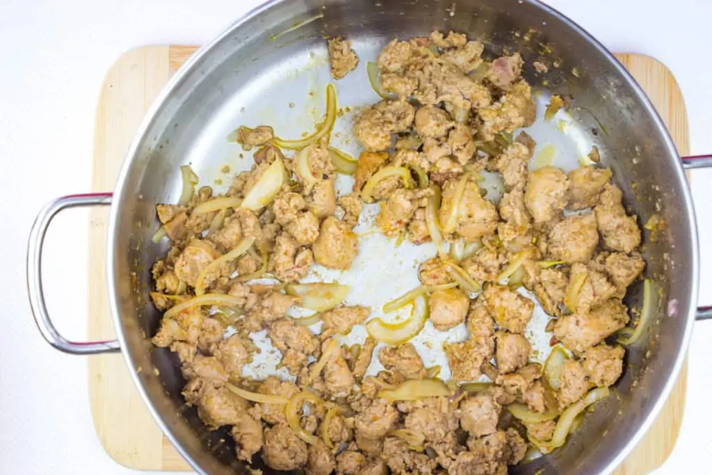 adding the onions and garlic to the sausage in a large pot