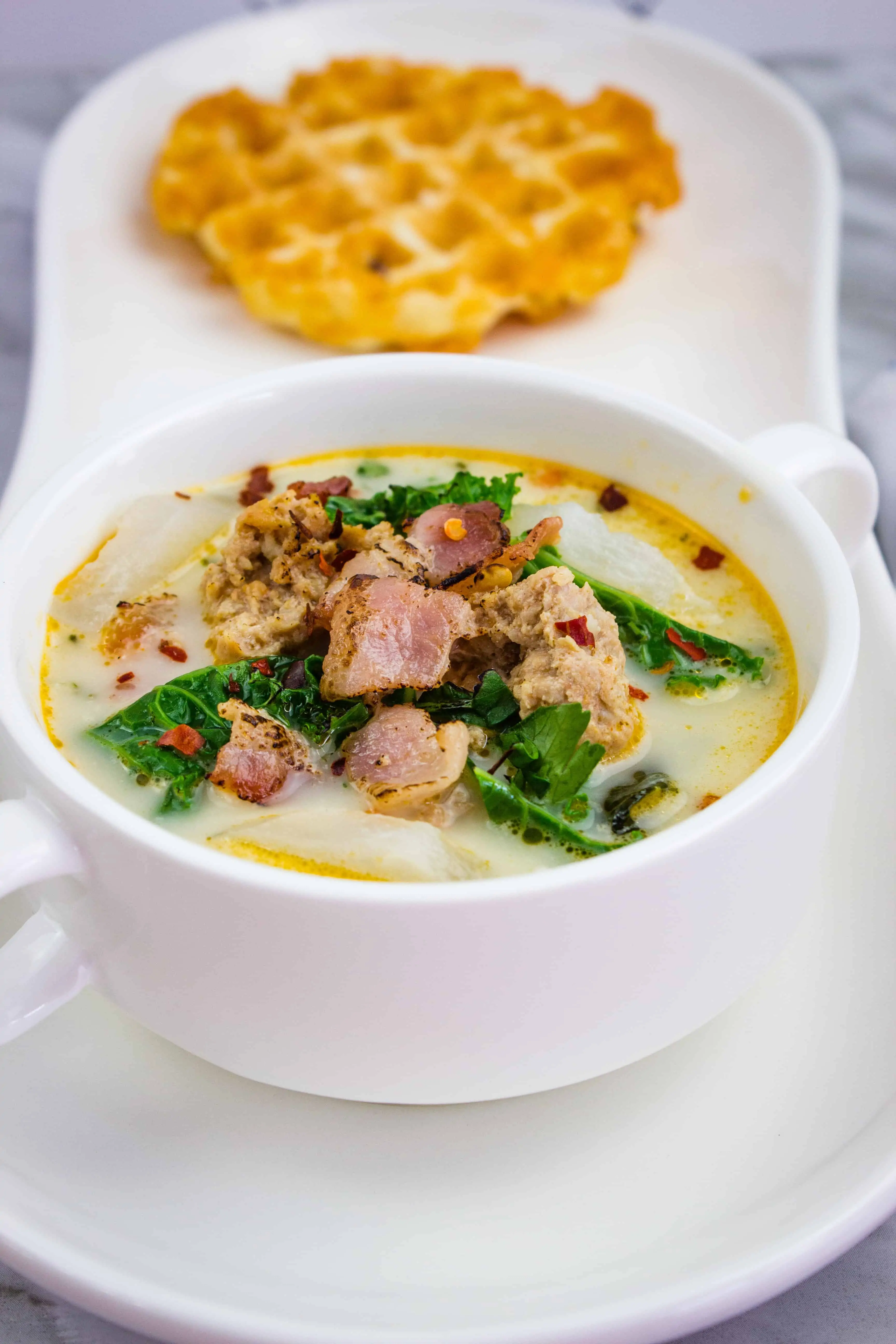 keto zuppa toscana soup in a bowl with a chaffle in the background