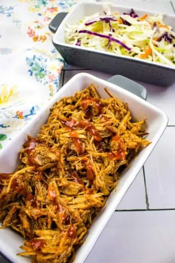 keto pulled pork in the instant pot in a serving dish with coleslaw in the background