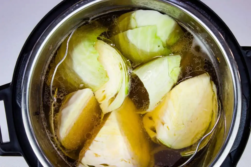 Cabbage wedges in the cooking liquid in an Instant Pot.