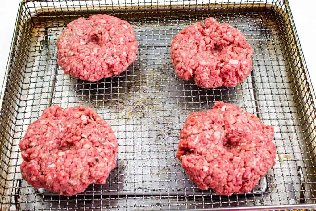 keto air fryer burgers with an indent in them on a pan 