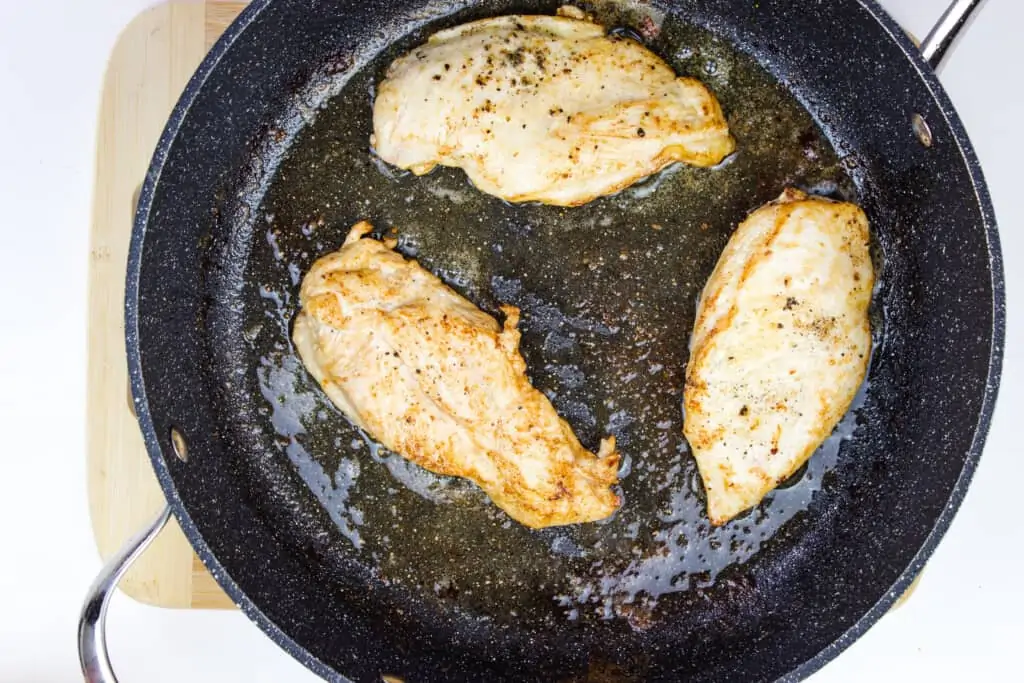 chicken breasts browning in a skillet.
