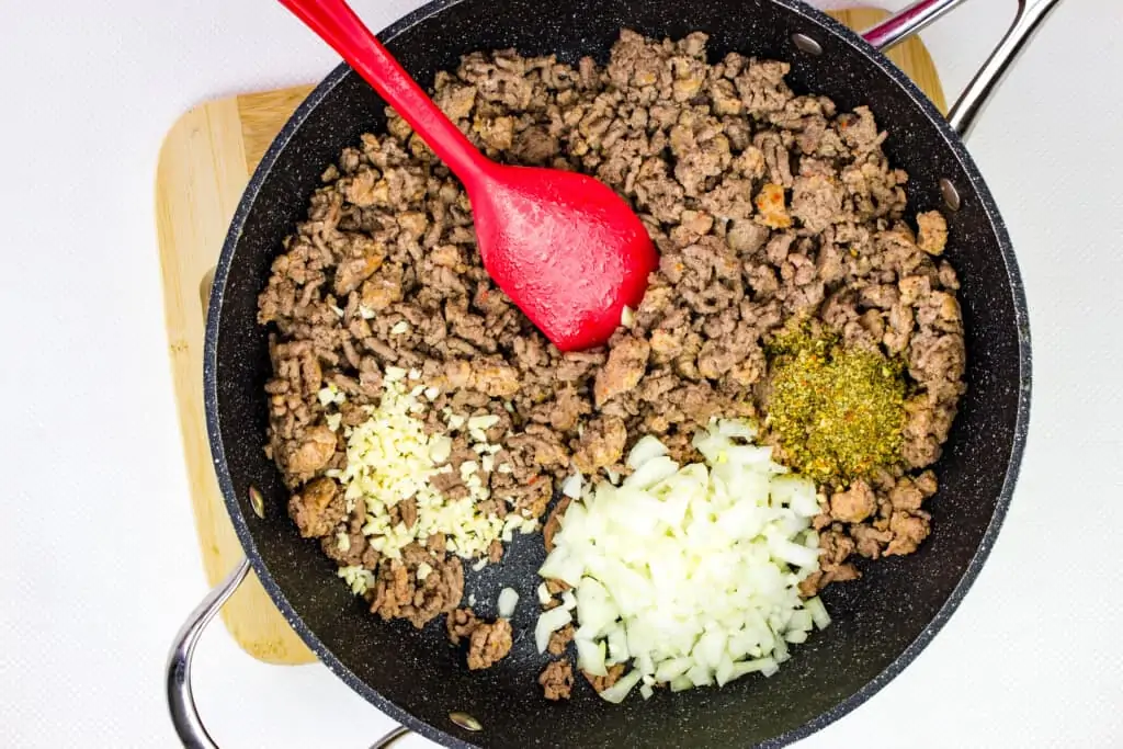 Adding the onions and seasoning to the skillet.