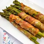 bacon wrapped asparagus on a white platter