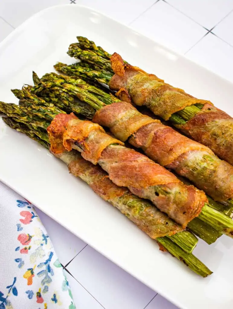 bacon wrapped asparagus on a white platter