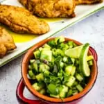 cucumber salsa in a bowl with smoked chicken in the background