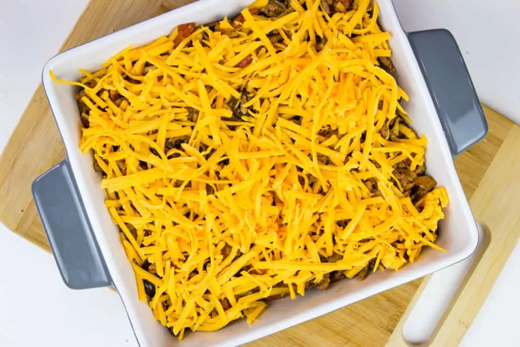 keto taco casserole topped with cheese and ready for the oven