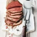 sliced roast beef on a board with a fork