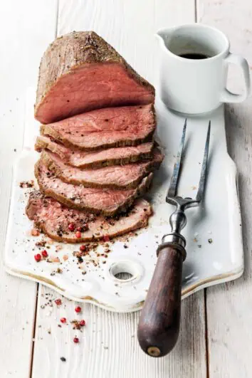 sliced roast beef on a board with a fork