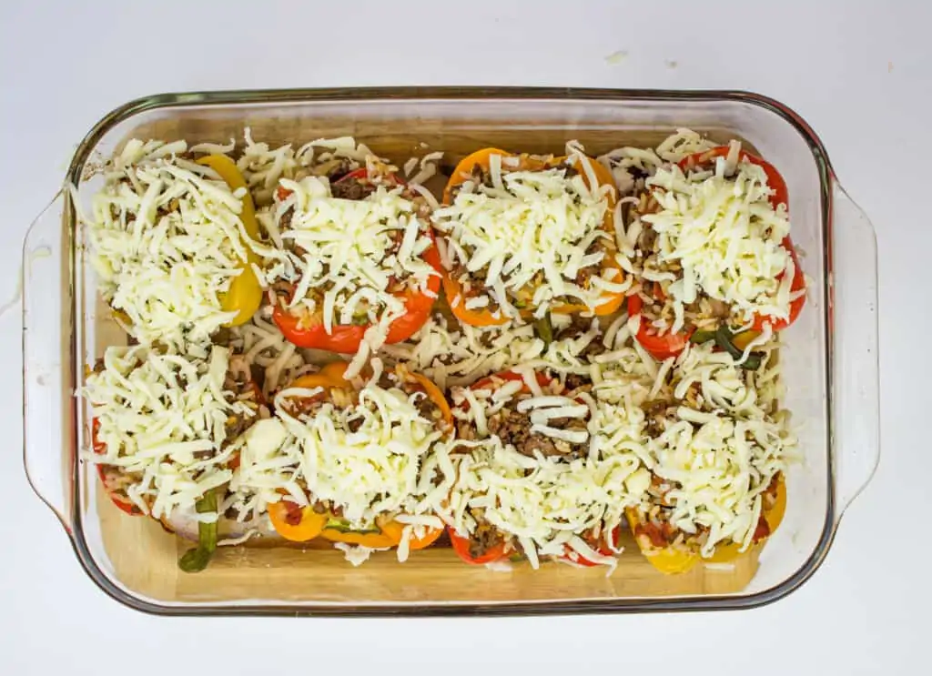 stuffed peppers topped with cheese ready for oven